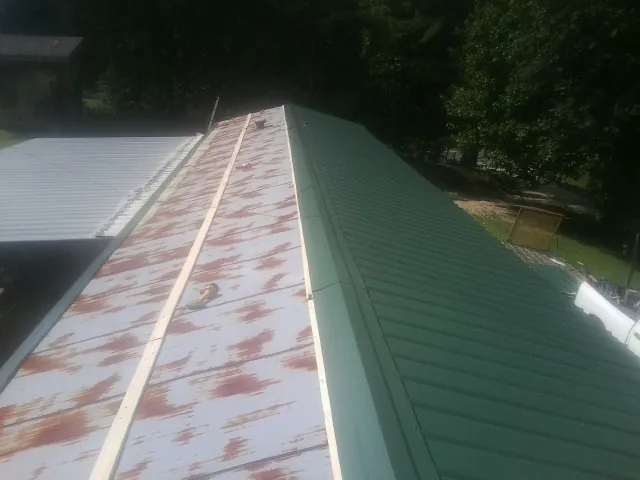 Old rusted panels beside newly installed green metal roofing — Wind Damage Roof Repair by Roofing Brothers in Glenside