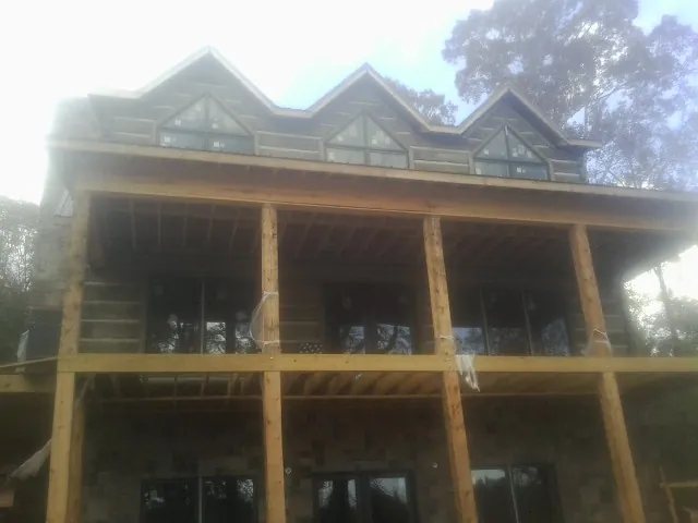 Dormers and porch framing on a large log home under construction — Roof Coating work by our crew in Glenside