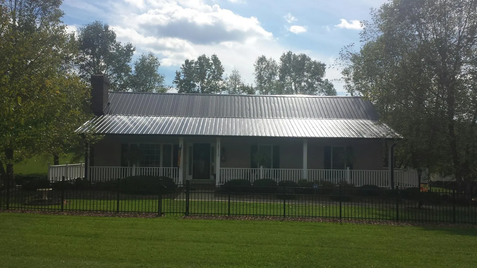 Gray metal roof on a brick ranch with a full width front porch — Gutter Guard Installation work by our crew in Glenside