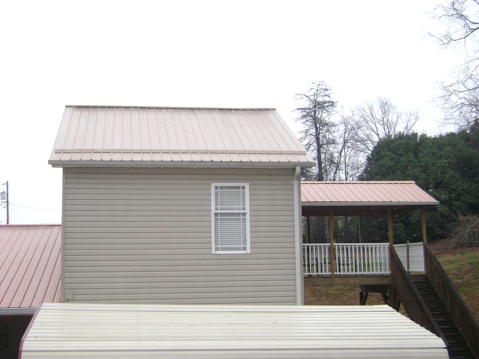 Tan metal roofs on a two story addition and attached porch, from a Roof Replacement job in Glenside