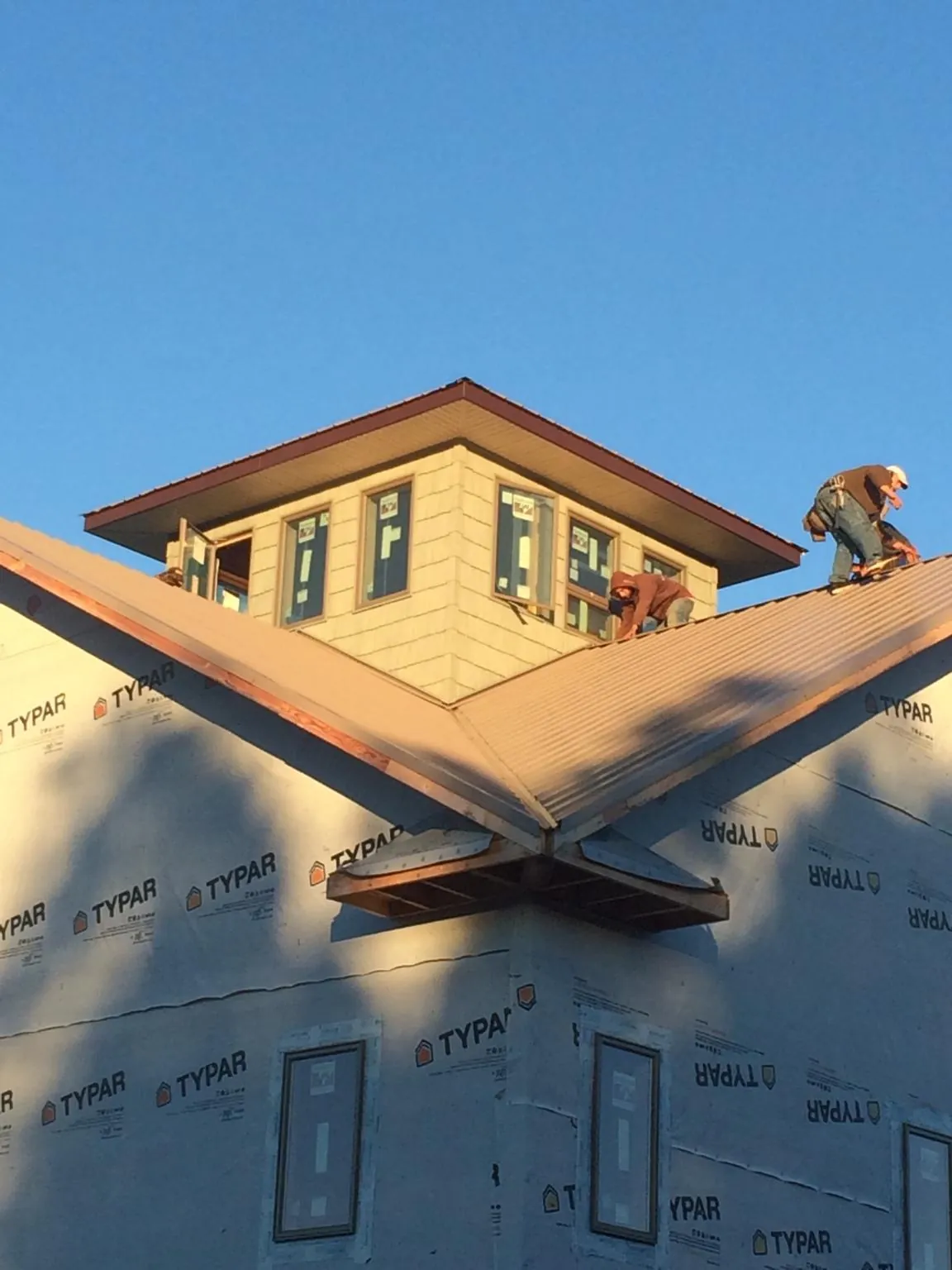 Roofers working around a rooftop cupola on a new metal roof at sunset — Roof Waterproofing in Glenside by Roofing Brothers